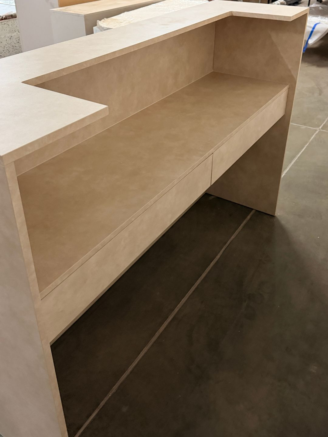 Beige reception desk with a desk featuring drawers